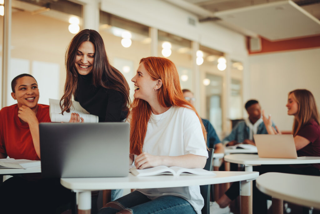 Female student talking with classmates and smiling in lecture room. University students in classroom after lecture.